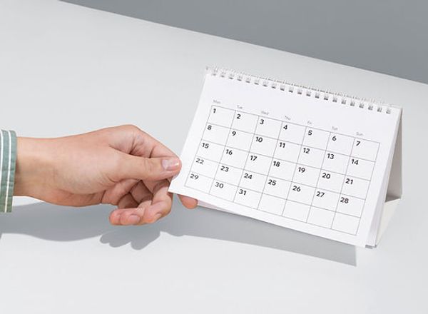 Hand zeigt auf einen Tischkalender zur Terminvereinbarung in einer hellen Praxisumgebung